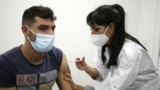 FILE - A young man receices a COVID-19 vaccine shot at a 24-hours vaccination center in Sarrola-Carcopino on the French Mediterranean island of Corsica, Jan. 8, 2022. 