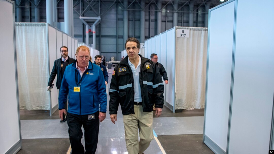In this March 27, 2020, photo provided by Office of Governor, Gov. Andrew Cuomo, right, walks the corridor of a nearly completed makeshift hospital erected by the U.S. Army Corps of Engineers at the Jacob Javits Convention Center in New York. 