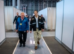 In this March 27, 2020, photo provided by Office of Governor, Gov. Andrew Cuomo, right, walks the corridor of a nearly completed makeshift hospital erected by the U.S. Army Corps of Engineers at the Jacob Javits Convention Center in New York.