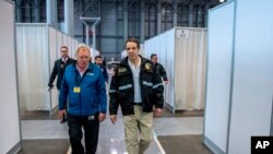 Gov. Andrew Cuomo, right, walks the corridor of a nearly completed makeshift hospital erected by the U.S. Army Corps of Engineers at the Jacob Javits Convention Center in New York, March 27, 2020.