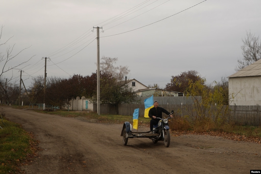 在一天前被乌军收复的赫尔松州布拉霍达特尼村，教师尤里·涅沃尔丘克开着插着乌克兰旗帜的摩托车，行驶在村中。(2022年11月11日)(photo:VOA)