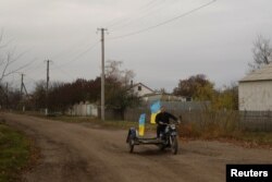 在一天前被乌军收复的赫尔松州布拉霍达特尼村，教师尤里·涅沃尔丘克开着插着乌克兰旗帜的摩托车，行驶在村中。(2022年11月11日)