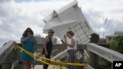 Tres mujeres visitan una playa para comprobar el alcance de los daños causados por el paso del huracán Nicole, incluyendo en un caseta de socorristas que fue desplazada hasta una duna, el 10 de noviembre de 2022, en Vero Beach, Florida. (AP Foto/Rebecca Blackwell)