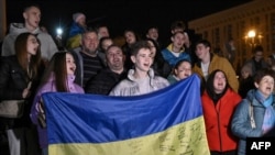 People hold a Ukranian flag as they gather in Maidan Square to celebrate the liberation of Kherson, in Kyiv, Nov. 11, 2022, amid the Russian invasion of Ukraine. 