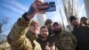 In this photo provided by the Ukrainian Presidential Press Office and posted on Facebook, Ukrainian soldiers take a selfie with President Volodymyr Zelenskyy, centre, during his visit to Kherson, Ukraine, Monday, Nov. 14, 2022. (Ukrainian Presidential Pre