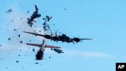 In this photo provided by Larry Petterborg, a Boeing B-17 Flying Fortress and a Bell P-63 Kingcobra collide in the midair during an airshow at Dallas Executive Airport in Dallas, Nov. 12, 2022. (Larry Petterborg via AP)
