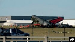 An emergency vehicle sits near debris from two planes that crashed during an airshow at Dallas Executive Airport, Saturday, Nov. 12, 2022.