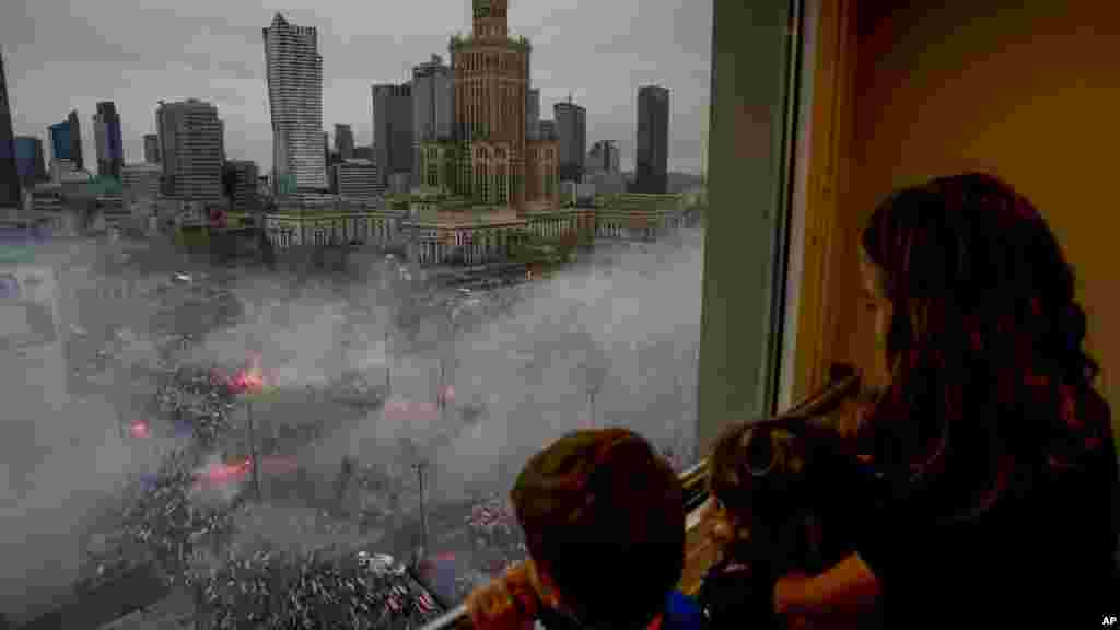 Children watch from a window as thousands of people gather in Warsaw's city center for a yearly march for Poland's National Independence Day organized by nationalist groups that has been marked by violence in past years.