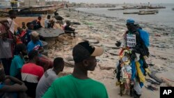 FILE:L Environmental activist Modou Fall at the Yarakh Beach littered by trash in Dakar, Senegal, Tuesday, Nov. 8, 2022. On his chest, poking out from the plastics hanging from him, is a sign in French that says "No to plastic bags." 