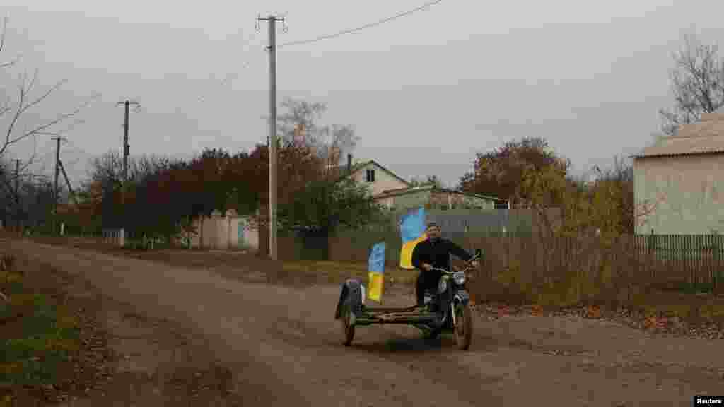 Teacher Yurii Nevolchuk rides a motorcycle with national flags in the village of Blahodatne in the Kherson region, retaken from Russia by the Ukrainian Armed Forces a day earlier.