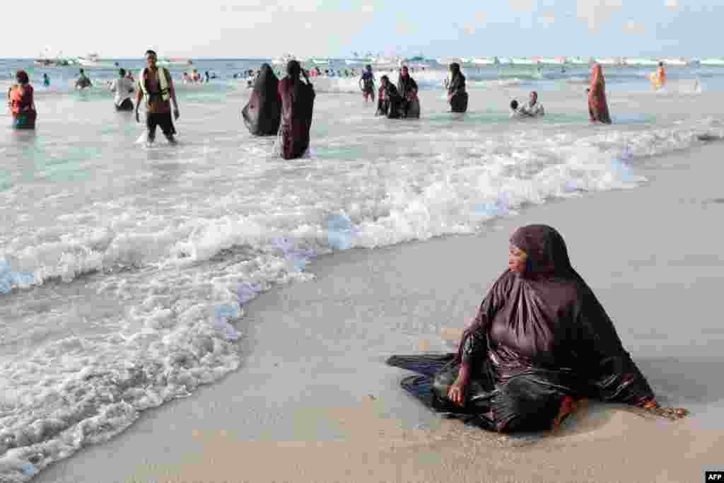 A women sits in the waters break at Lido beach early in the morning in Mogadishu, Somalia.