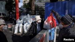 A delivery driver hands food to a resident of an apartment compound that was placed under lockdown as outbreaks of COVID-19 continue in Beijing, China, Nov. 12, 2022