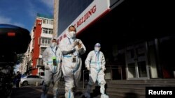 Petugas pencegahan pandemi mengenakan APD berjalan di dekat kompleks apartemen yang di-lockdown, di tengah merebaknya kembali COVID-19 di Beijing, Cina, 12 November 2022. (REUTERS/Thomas Peter)