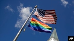 FILE - A gay pride rainbow flag flies with the US flag in front of the Asbury United Methodist Church in Prairie Village, Kan., on April 19, 2019.