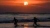 Dua orang tampak berkejar-kejaran di laut saat matahari terbenam di Pantai Mesari, Seminyak, Bali pada 21 Juni 2022. (Foto: AFP/Sonny Tumbelaka)