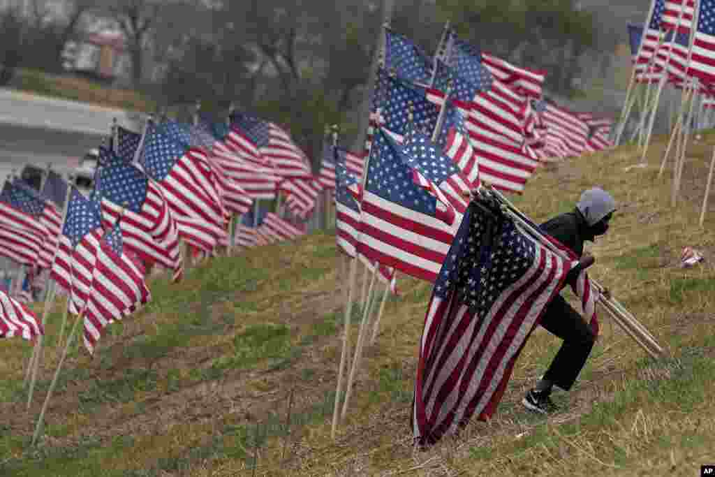 A volunteer gathers flags that were part of a display of 175 flags that were on a hillside overlooking Interstate 35 to commemorate Veterans Day, Nov. 12, 2022, in Merriam, Kan. 