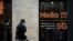 FILE - A man talks on a mobile phone as he walks past a store of French telecom group Orange advertising the 5G service on its shop window, in Bordeaux, southwestern France, on February 23, 2021.