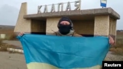 一名烏克蘭士兵在南部赫爾松地區的一個村莊里展示烏克蘭國旗。 （2022年11月11日）