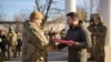 This handout photograph taken and released by Ukrainian Presidential press service on November 14, 2022, shows Ukrainian President Volodymyr Zelensky (R) awarding a Ukrainian serviceman during his visit to the city of Kherson. (Photo by Handout / Ukrainia