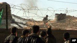 An Egyptian soldier (top R) takes position in the Egyptian side of Rafah as Palestinian demonstrators stand on their side of the divided border town during clashes, 06 Jan 2010