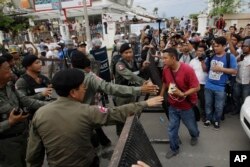 FILE - Riot police officers stop journalists from entering a blocked main street near the Cambodia National Rescue Party (CNRP) headquarters, on the outskirts of Phnom Penh, Cambodia, Monday, May 30, 2016.