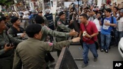 In this photo taken on May 30, 2016, riot police officers stop journalists from entering a blocked main street near the Cambodia National Rescue Party (CNRP) headquarters, on the outskirts of Phnom Penh, Cambodia.