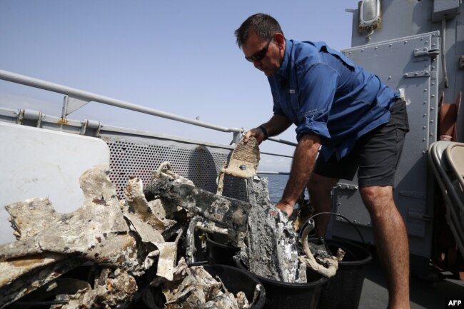 A staff member of the U.S. agency the Defense POW/MIA Accounting Agency inspects, July 2, 2018, fragments of the USAAF P-47 Thunderbolt U.S. fighter plane, that crashed during World War II, off the French Mediterranean island of Corsica.