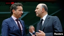 Eurogroup chairman Jeroen Dijsselbloem (L) talks to European Commissioner for economics, taxation and customs Pierre Moscovici (R) during an eurozone finance ministers meeting in Brussels, Jan. 26, 2015. 