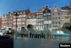 FILE - Reflections of tourists and canal houses are seen in the window of the Anne Frank museum in Amsterdam, April 24, 2013.