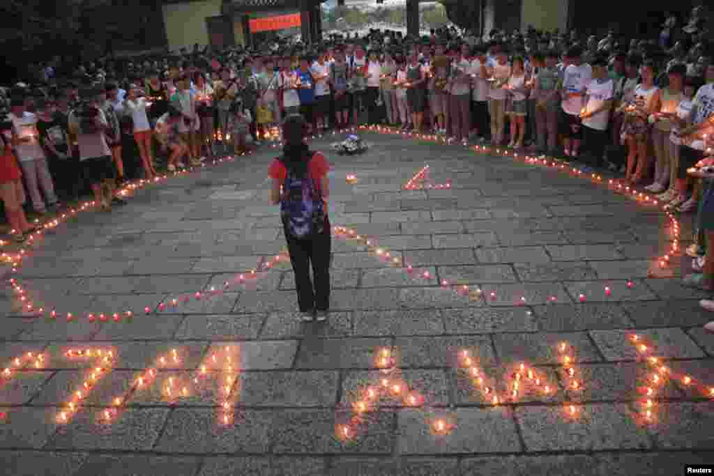 Students of the Jiangshan Middle School light candles to form a heart shape and initials of the victims Yang Mengyuan and Wang Linjia of the Asiana Airlines crash, in Quzhou, Zhejiang province July 8, 2013.