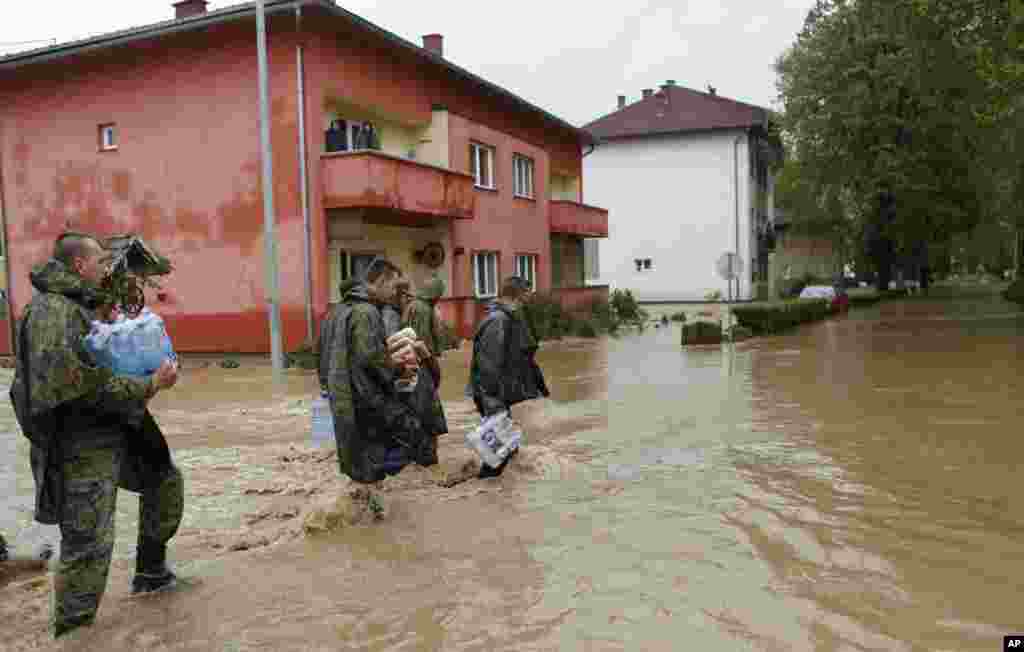 Members of the army carry food and water supplies for people stranded, due to the floods, in the Bosnian town of Maglaj, May 16, 2014.