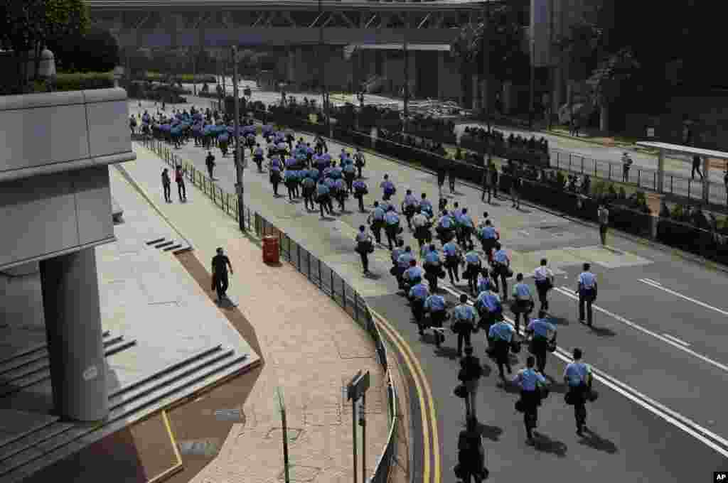 Police officers run to the barricades that protesters have set up to block off main roads in Central district in Hong Kong, Oct. 14, 2014.