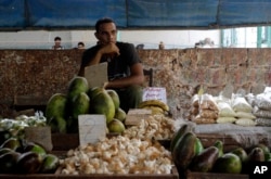 FILE - A food vendor sits by his goods at a popular market in Havana, Cuba, Aug. 27, 2010.