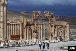 A picture taken on March 14, 2014 shows Syrian citizens walking in the ancient oasis city of Palmyra, 215 kilometres northeast of Damascus.