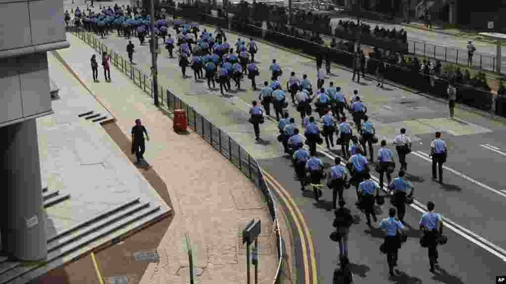 Des policiers courent sur ​​les barricades que les manifestants ont mis en place pour bloquer les routes principales dans le quartier central de Hong Kong 14 octobre 2014. (AP Photo / Kin Cheung) 