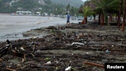 Un hombre camina por la playa cubierta de ramas de árboles y esc.ombros después del paso del huracán Rick en Zihuatanejo, en el estado de Guerrero, México, el 25 de octubre de 2021