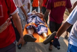 People carry an injured resident, who was shot with rubber bullets, as security force destroyed barricades erected by protesters against the military coup, in Yangon on March 9, 2021.