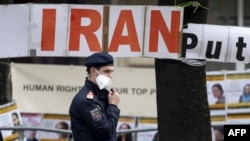 Policajac patrolira ispred transparenta koji su postavili članovi Nacionalnog vijeća otpora Irana, iranske opozicione grupe, ispred hotela u Beču tokom nuklearnih pregovora s Iranom 27. aprila, 2021.