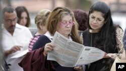 Para pemilih di Hialeah, Florida, membaca contoh kertas suara saat mengantre di TPS. (Foto: AP)