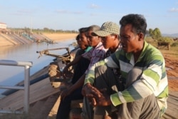 Farmers watch over an irrigation canal and as they wait to demand authorities pump more water into the irrigation system in Pursat province’s Bakan district, December 18, 2019 (Sun Narin/VOA Khmer)