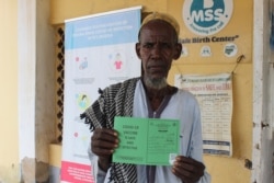 A man displays his Moderna COVID-19 vaccination certificate at the Gaube comprehensive primary health care center in Kuje, Nigeria on Sept. 1, 2021.