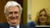 Suspected war criminal and former Bosnian Serb leader Radovan Karadzic smiles as he takes his seat on the defense bench in a courtroom to start his defense at the U.N. war crimes tribunal in The Hague, Netherlands, October 16, 2012. 