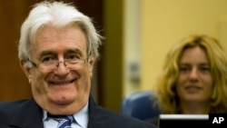 Suspected war criminal and former Bosnian Serb leader Radovan Karadzic smiles as he takes his seat on the defense bench in a courtroom to start his defense at the U.N. war crimes tribunal in The Hague, Netherlands, October 16, 2012. 