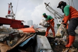 Sejumlah petugas kebersihan pemda membersihkan sampah dari pinggir pantai di Pelabuhan Kali Adem, Jakarta, 8 Juni 2021. (Foto: Willy Kurniawan/Reuters)