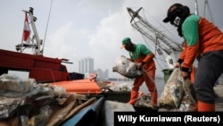 Sejumlah petugas kebersihan pemda membersihkan sampah dari pinggir pantai di Pelabuhan Kali Adem, Jakarta, pada 8 Juni 2021. (Foto: Willy Kurniawan/Reuters)