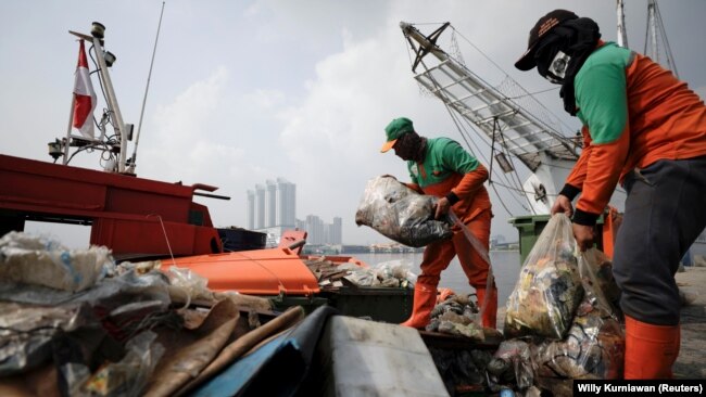 Sejumlah petugas kebersihan pemda membersihkan sampah dari pinggir pantai di Pelabuhan Kali Adem, Jakarta, pada 8 Juni 2021. (Foto: Willy Kurniawan/Reuters)