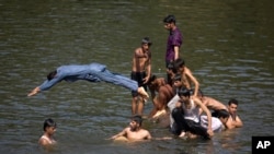 Orang-orang mendinginkan diri dengan berendam diri di sungai untuk mengurangi sengatan udara panas saat suhu mencapai 38 Celcius pada bulan suci Ramadan, Senin 29 Mei 2017, di Islamabad, Pakistan. (AP Photo/B.K. Bangash)