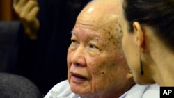 In this photo released by the Extraordinary Chambers in the Courts of Cambodia, Khieu Samphan, left, former Khmer Rouge head of state, sits in the court room during a hearing at the U.N.-backed war crimes tribunal, in Phnom Penh, Cambodia, Friday, Oct. 17, 2014. A U.N.-backed Cambodian tribunal has begun hearing the first genocide case against the country's brutal 1970s Khmer Rouge regime. (AP Photo/Extraordinary Chambers in the Courts of Cambodia, Nhet Sok Heng)