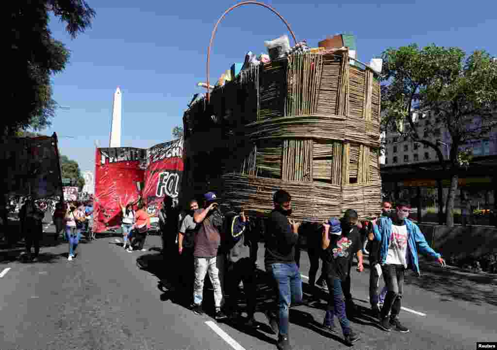 Demonstrators carry a basket with basic products made of cardboard as a protest to demand better wages and economic conditions, in Buenos Aires, Argentina, April 13, 2021.