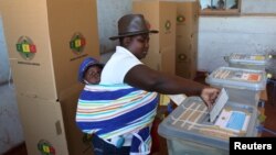 FILE: A woman with a baby on her back casts her ballot in the country's general elections in Harare, Zimbabwe, July 30, 2018. 